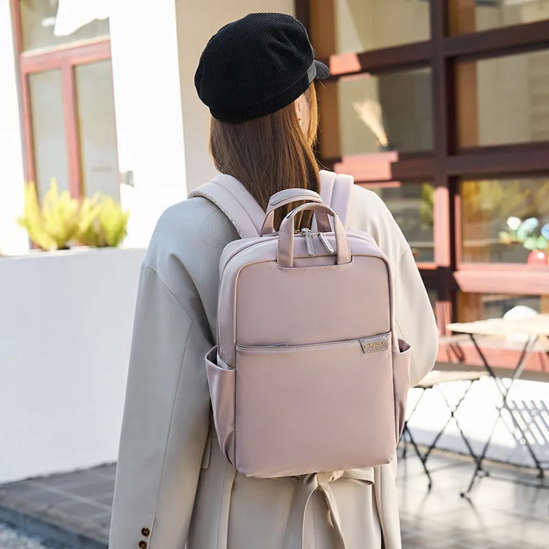 Nylon women's travel backpack in apricot colour showing front pockets and laptop compartment.