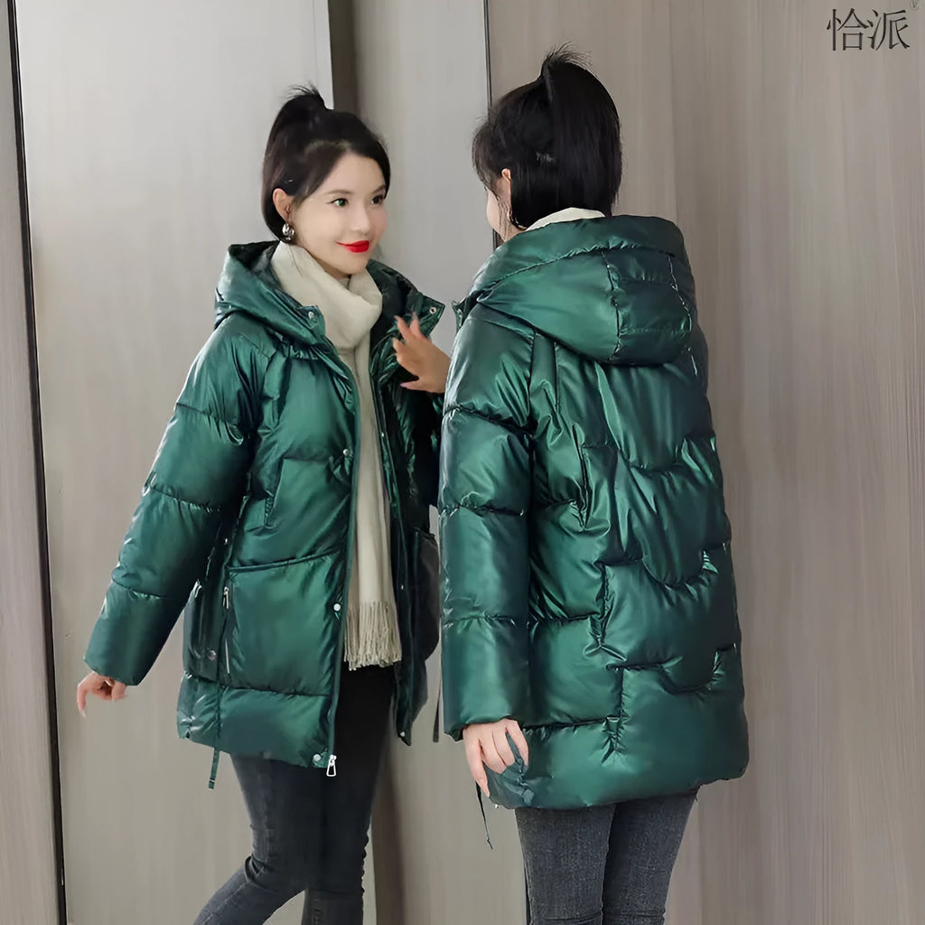 A woman wears a loose-fitting green hooded winter jacket with long sleeves.