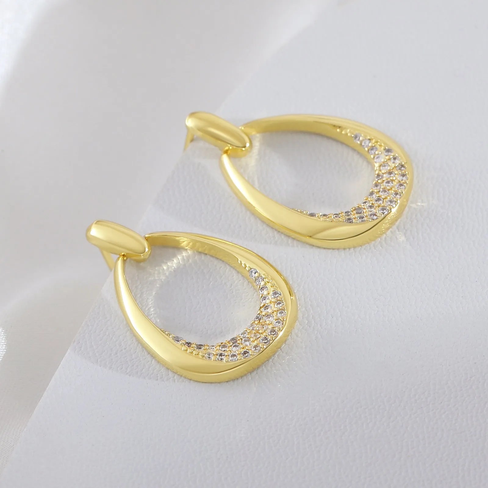Yellow gold geometric drop earrings for women with round and oval elements, shown with handbag packaging.