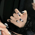 Black and pink heart hand-painted artificial nails with bow detailing in mid-length cat's eye design