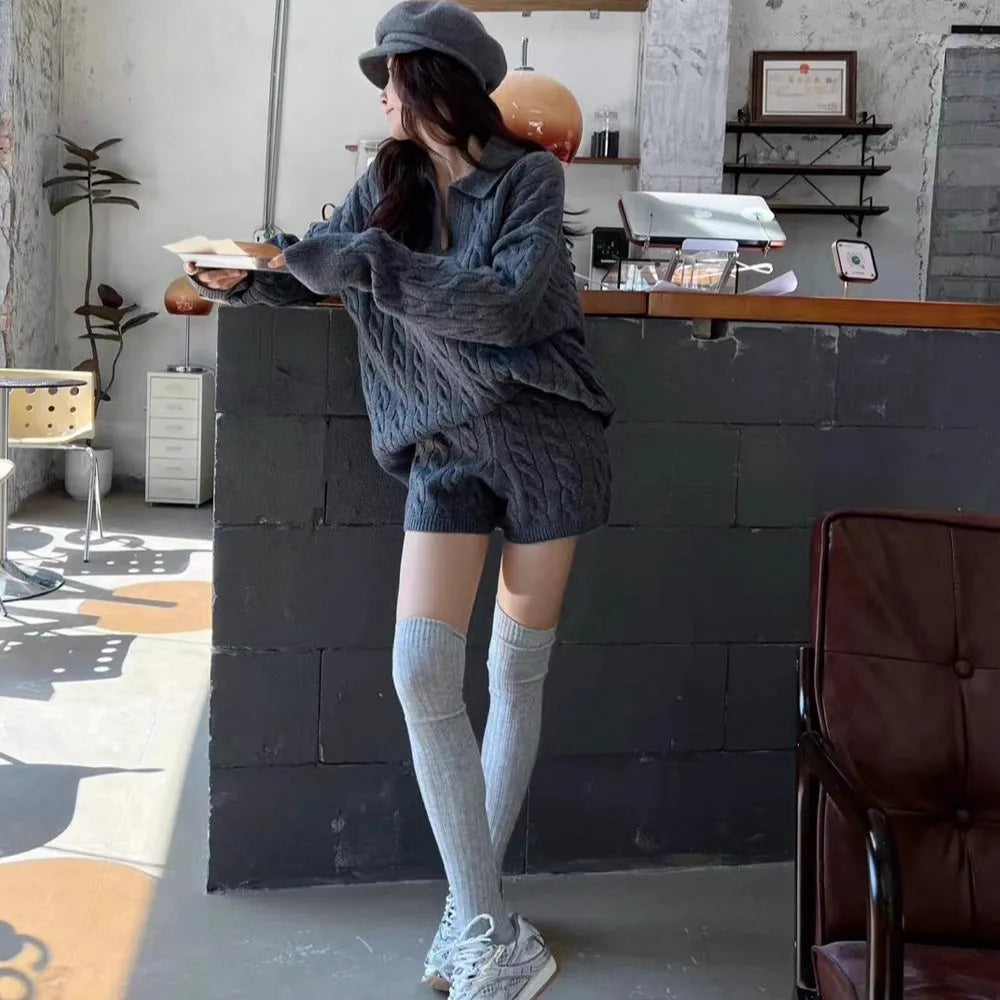 Women's knitted suit set showing geometric pattern cable knit sweater and elastic waist shorts in black colour