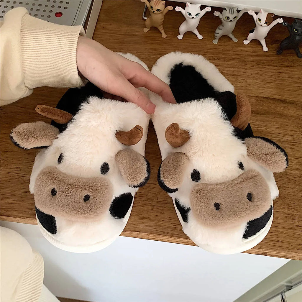 White cow plush slippers with non-slip textured soles shown from above