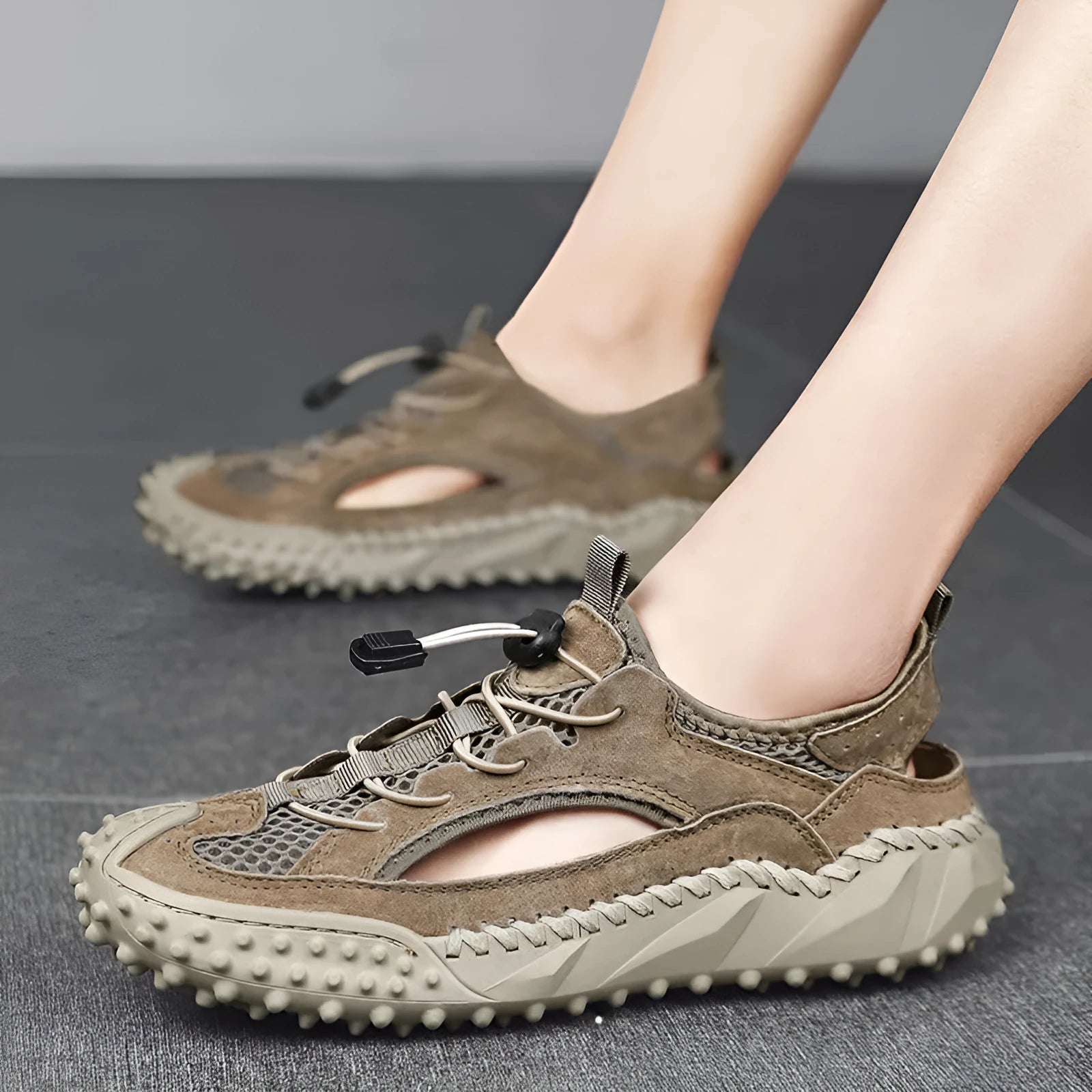 Men's black sports sandal with leather mesh upper, elastic band, and textured rubber sole.