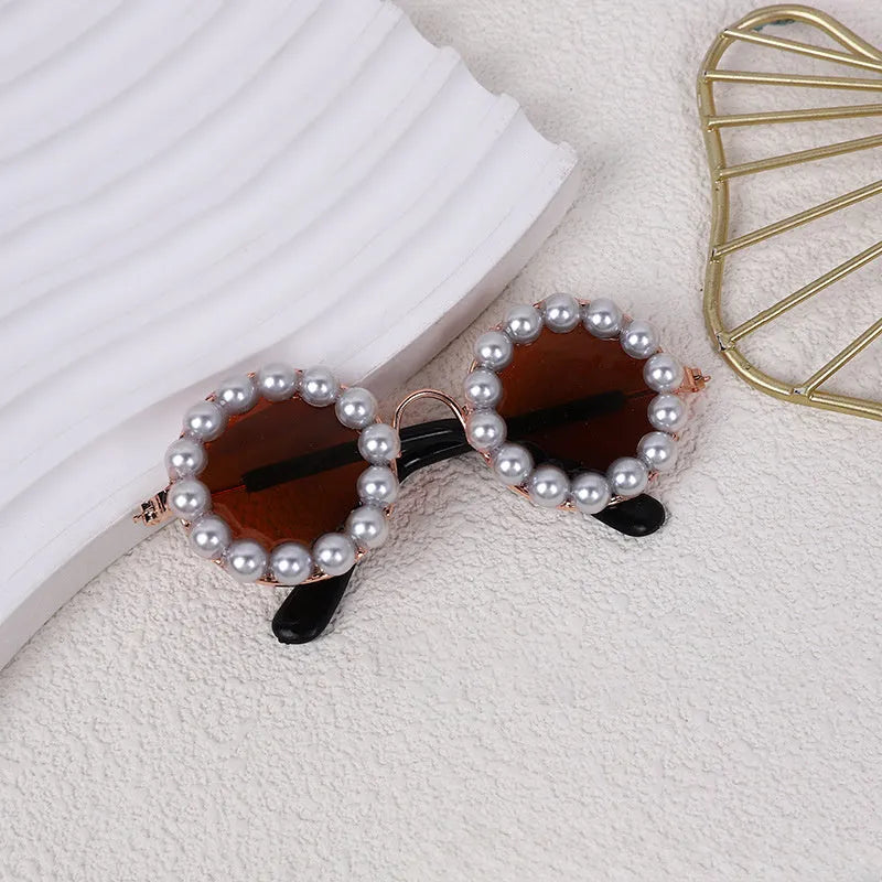 Pearl-rimmed round sunglasses for a cat or dog on a festive background.