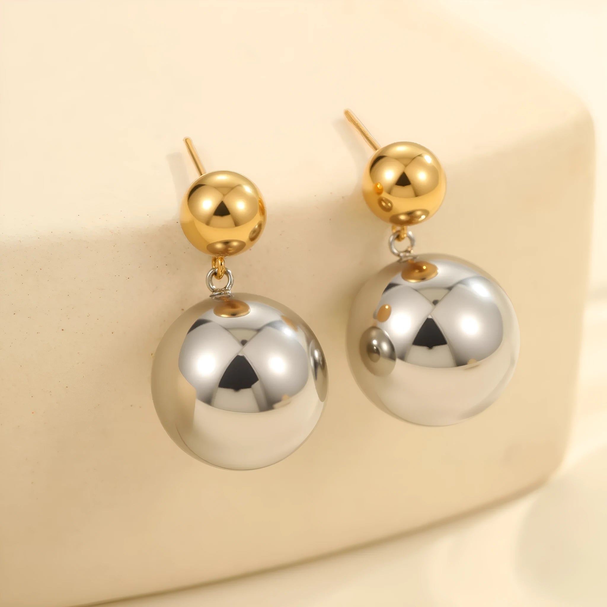A pair of stainless steel stud earrings with 18K gold electroplated colour-block finish and round bead geometry design.