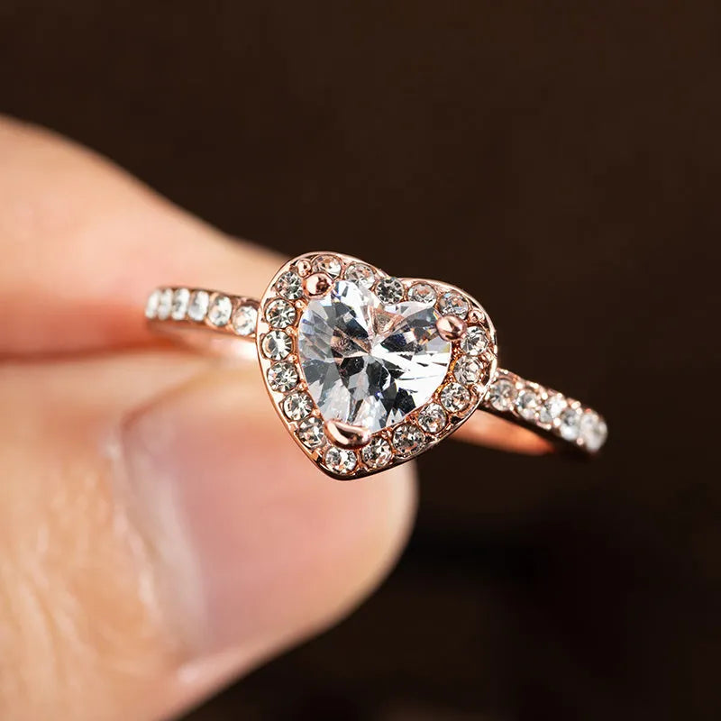 Close-up of a women's heart-shaped ring with a clear crystal centre in rose gold or silvery finish.