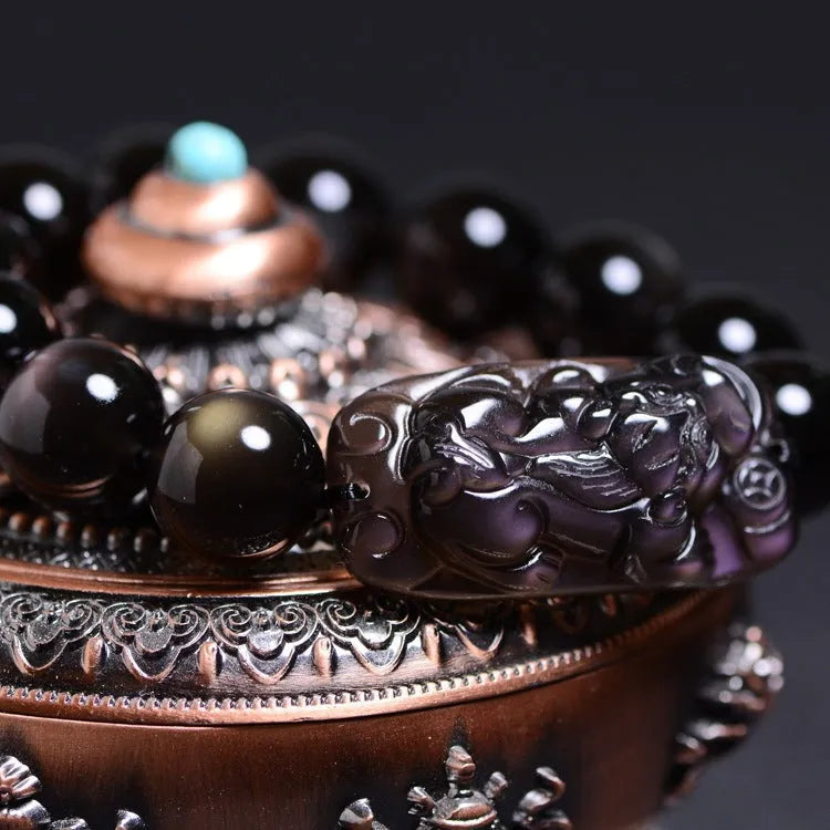 A polished crystal Pi Xiu bracelet with geometric beads on a white background.