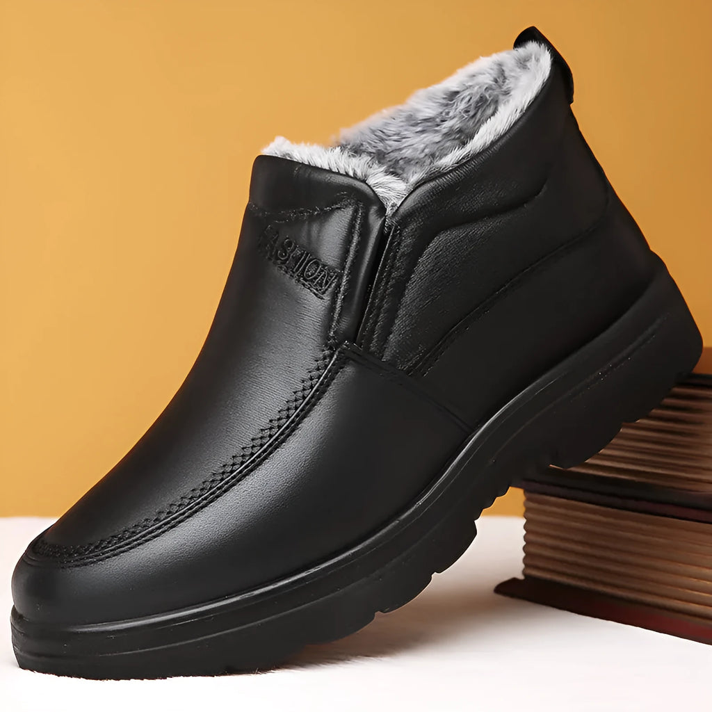 Men's black fleece-lined winter slip-on shoes with rubber sole on a wooden floor.