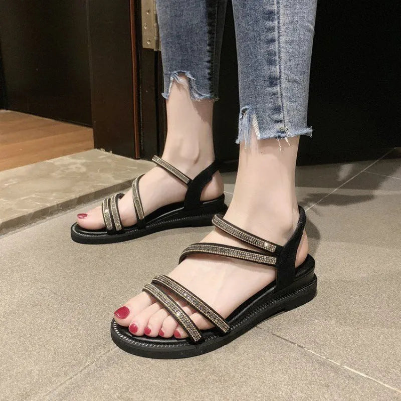 Women's silver flat sandals with rhinestone decoration and an elastic band across the foot.