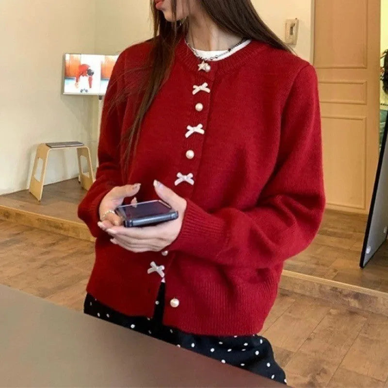 Women's solid colour cashmere cardigan with bow detail and pearl buttons on a hanger