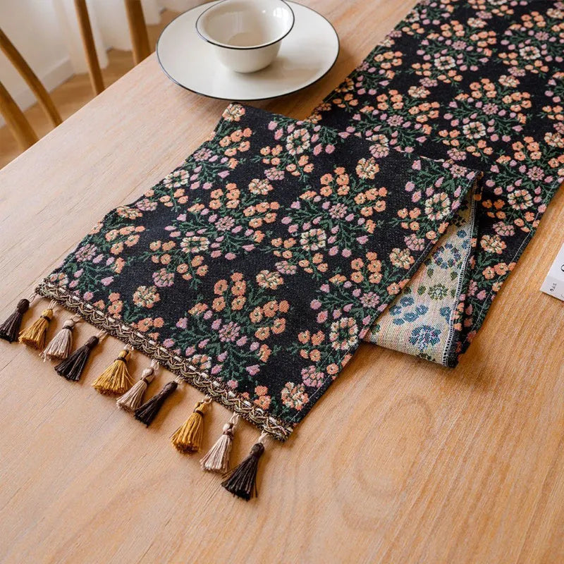 Dark blue striped Nordic jacquard bouquet table runner with tassel trim laid flat on a table.