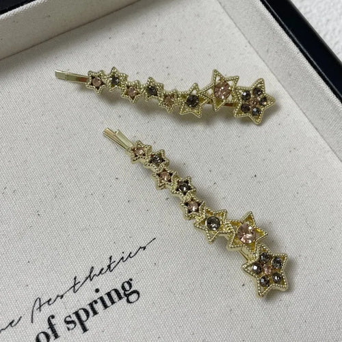 Gold electroplated alloy barrette with five-pointed star rhinestone design and broken clip construction