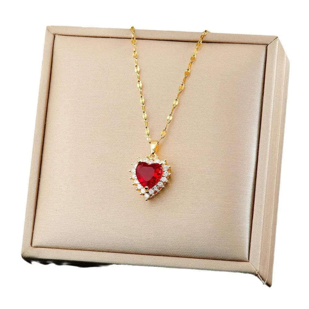 Gold red titanium steel heart jewellery set with gemstone inlay, showing necklace, earrings, and ring.