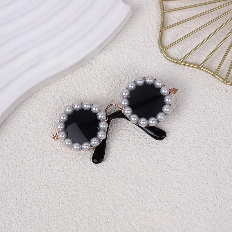 Pearl-rimmed round sunglasses for a cat or dog on a festive background.
