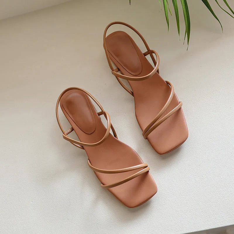 Women's beige flat strap Roman sandals with an open toe and square toe bracket on a white background.