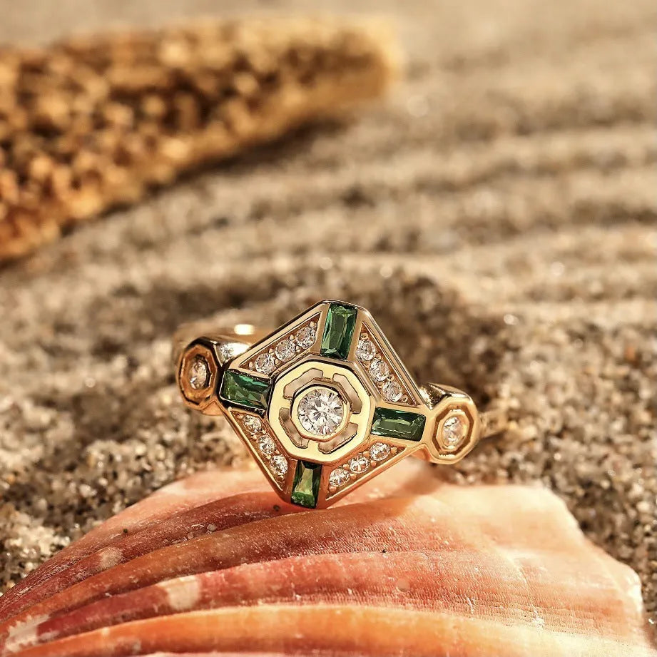 Women's square geometric fashion ring with a green emerald-coloured stone on an electroplated band.