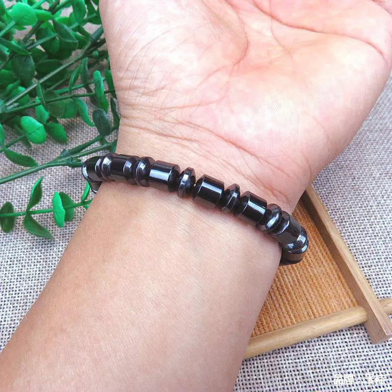Black pentagram magnetic bracelet with magnetite and hematite stones on a wrist.