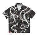 Man wearing a loose fit short sleeve Cuban collar shirt with a snake bone and floral pattern print.