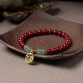 Gold cinnabar and copper bead bracelet in a wave shape on a wrist.