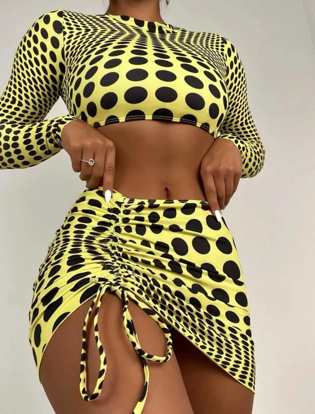 Women's green polka dot three-piece swimsuit set with bra top and skirt on hanger