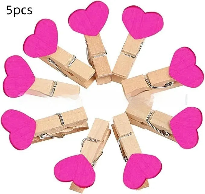 Five small handmade solid wood heart-shaped clips in assorted colours on a white surface.