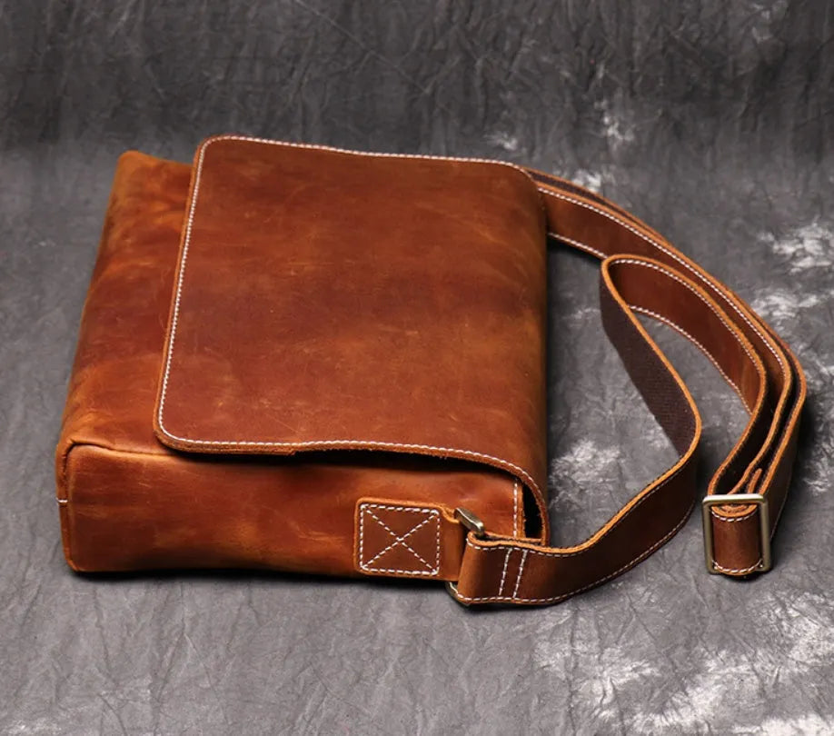 Brown vintage leather men's messenger bag with a flap opening and an adjustable shoulder strap.