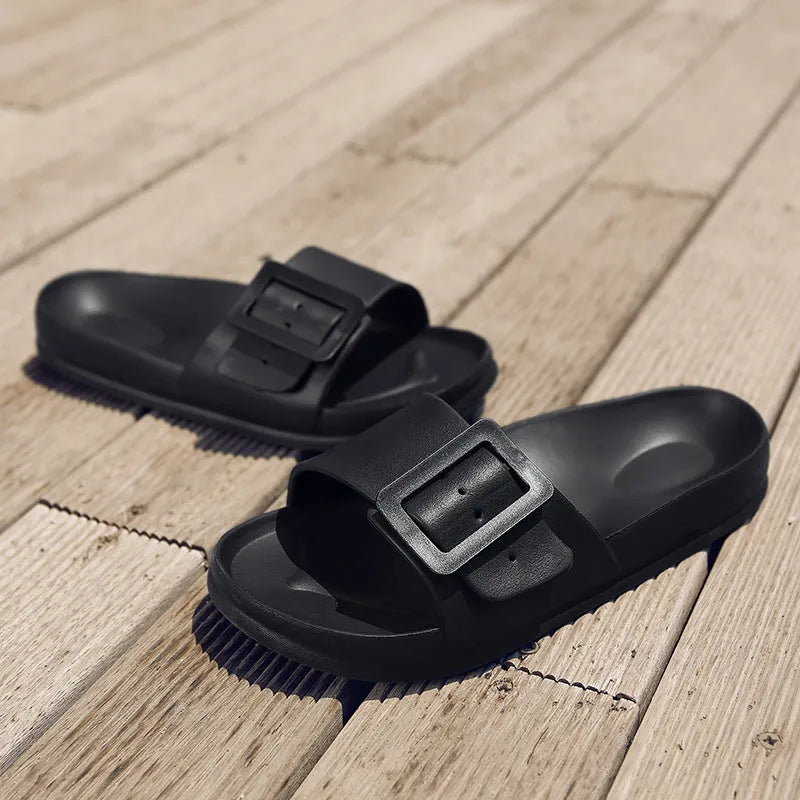 Women's grey blue EVA buckle slippers on a light background, showing the adjustable strap and textured sole.
