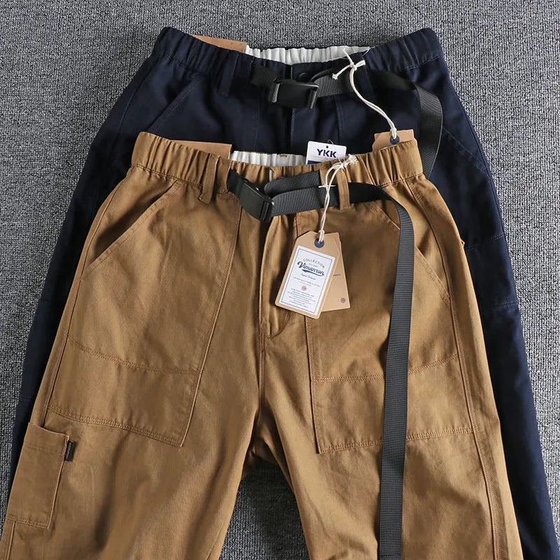 Men's khaki work trousers with a buckle belt and three-dimensional cutting on a hanger.