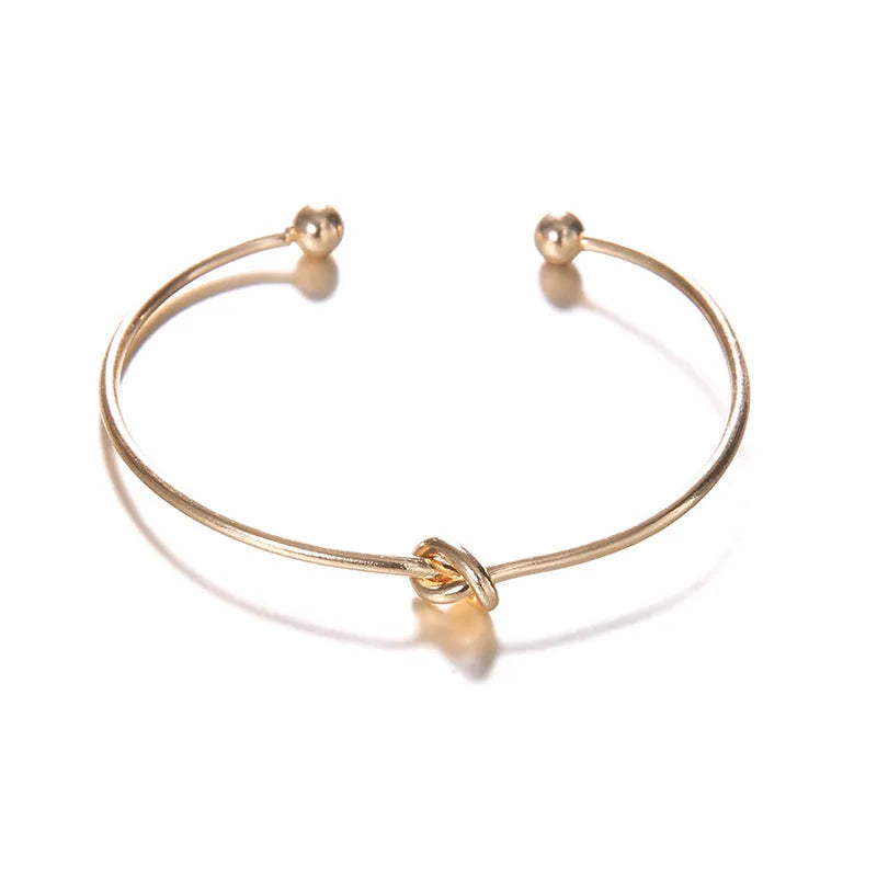 Gold-toned vintage women's cuff bracelet with an intricate arrow knot design.