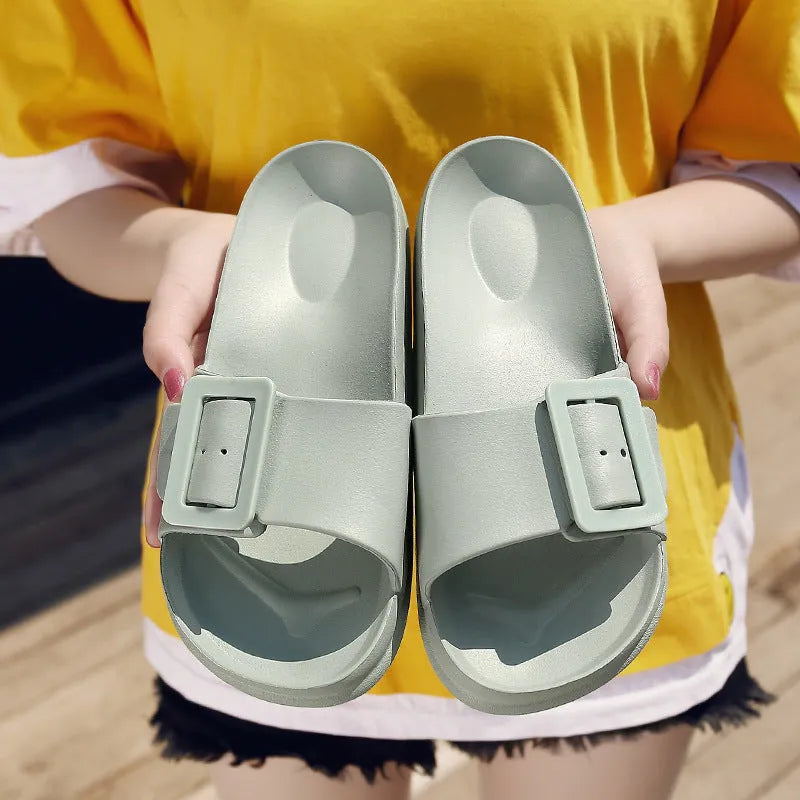 Women's grey blue EVA buckle slippers on a light background, showing the adjustable strap and textured sole.