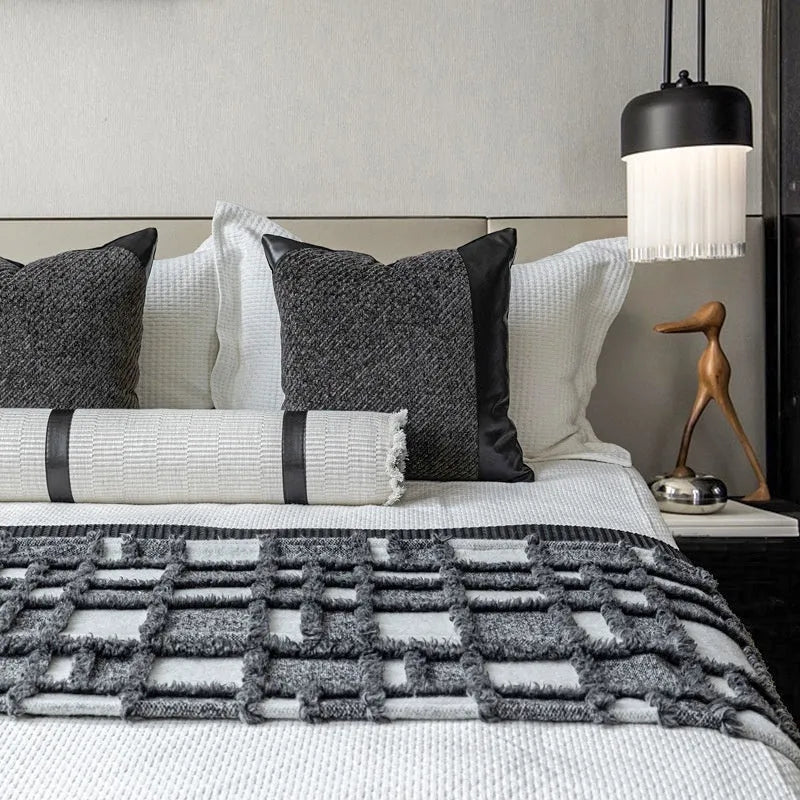 Grey and white plaid polyester bed runner blanket with matching pillowcase and leather round pillow on a double bed.