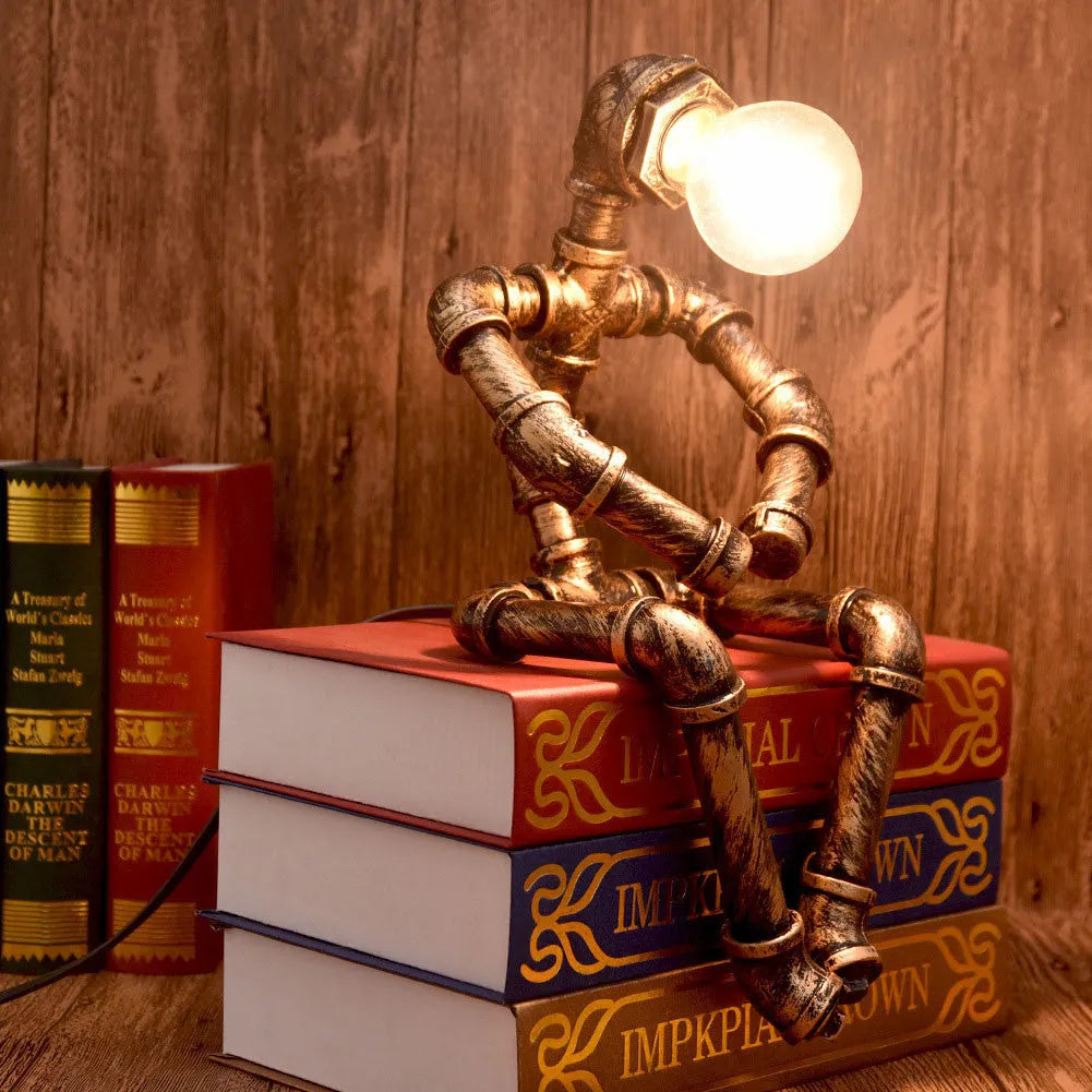 Green bronze vintage industrial robot desk lamp with iron pipe design on a wooden table.