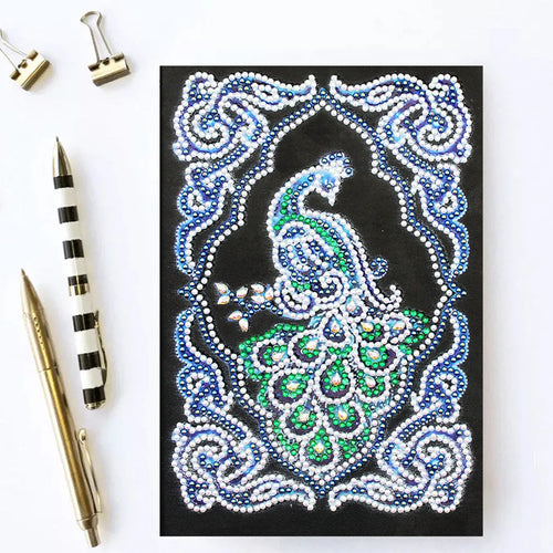 Black A5 diamond painting notebook with a peacock design cover, shown closed.