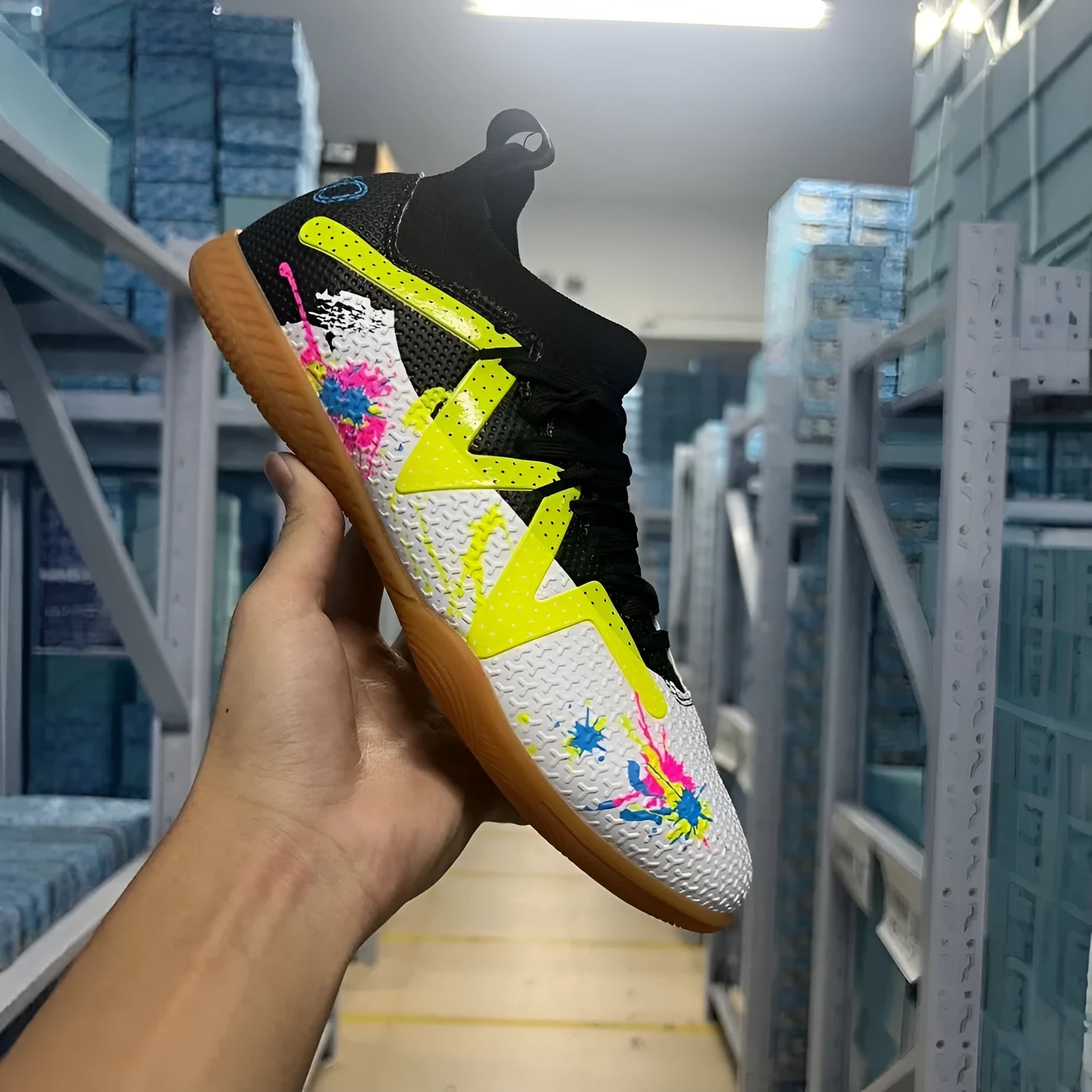 Lining low-top football boots in black and yellow with spiked rubber sole, showing mesh and PVC upper construction.