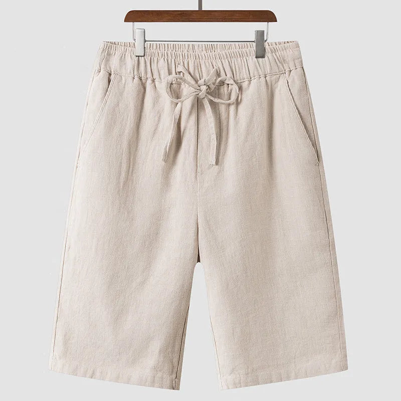 Men's beige linen casual shorts with loose cropped fit and elastic waistband laid flat