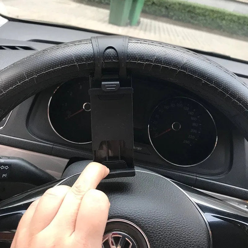 Black steering wheel phone holder clip mounted on car steering wheel holding a smartphone