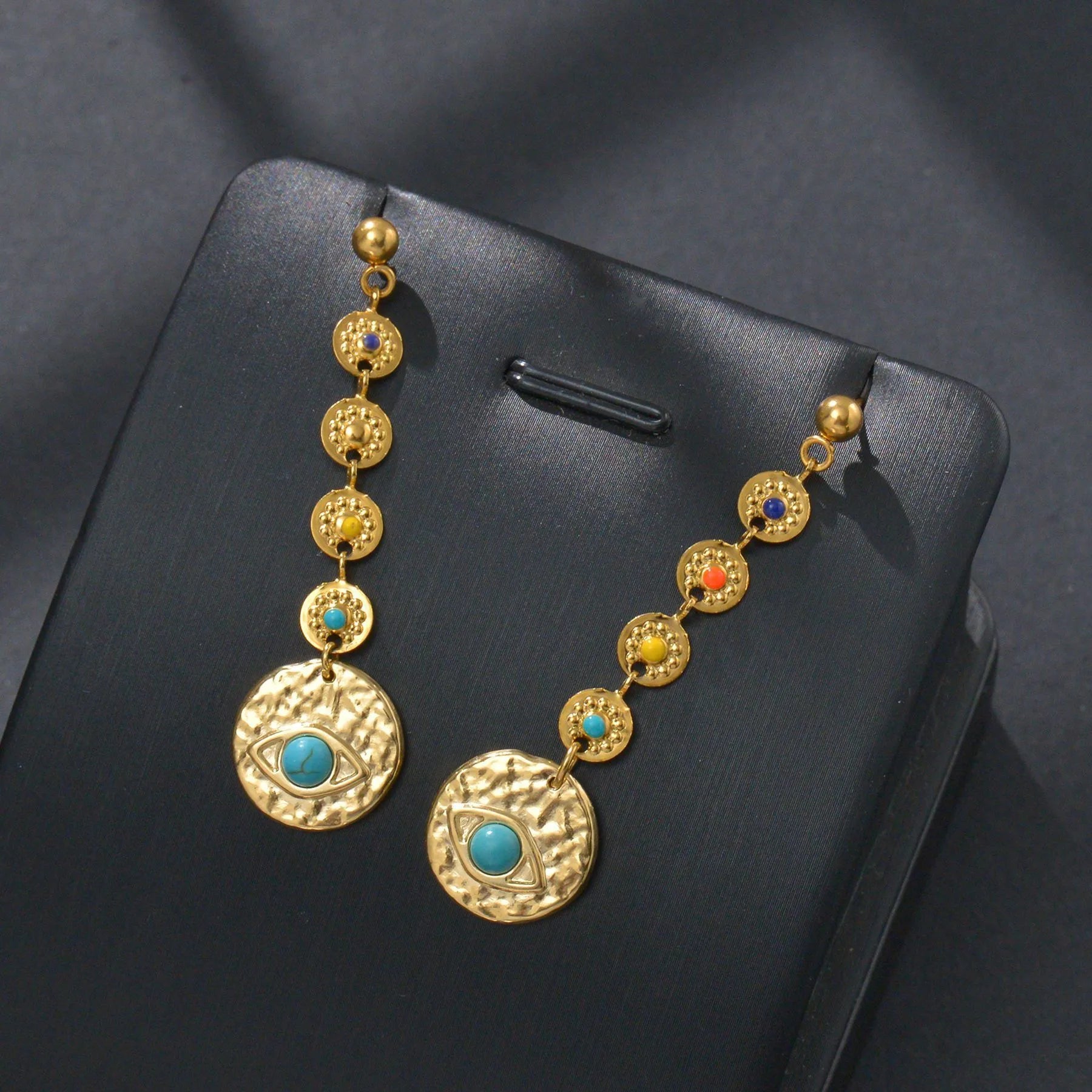 Stainless steel geometric drop earrings showing eight-awn star, eye, and shell sun designs in silver tone