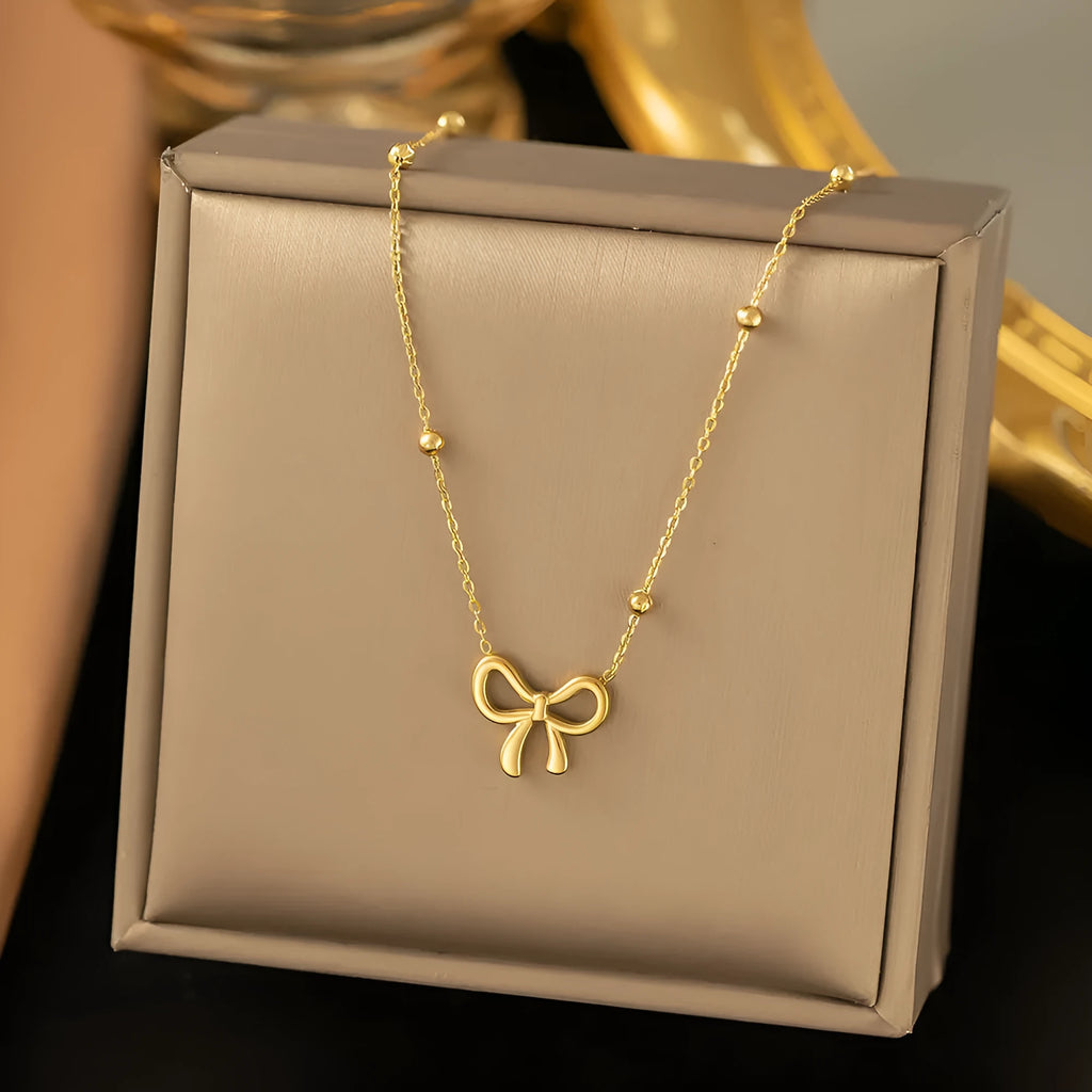 Gold electroplated bow necklace on a titanium steel cross chain, adjustable from 41 to 50 cm.