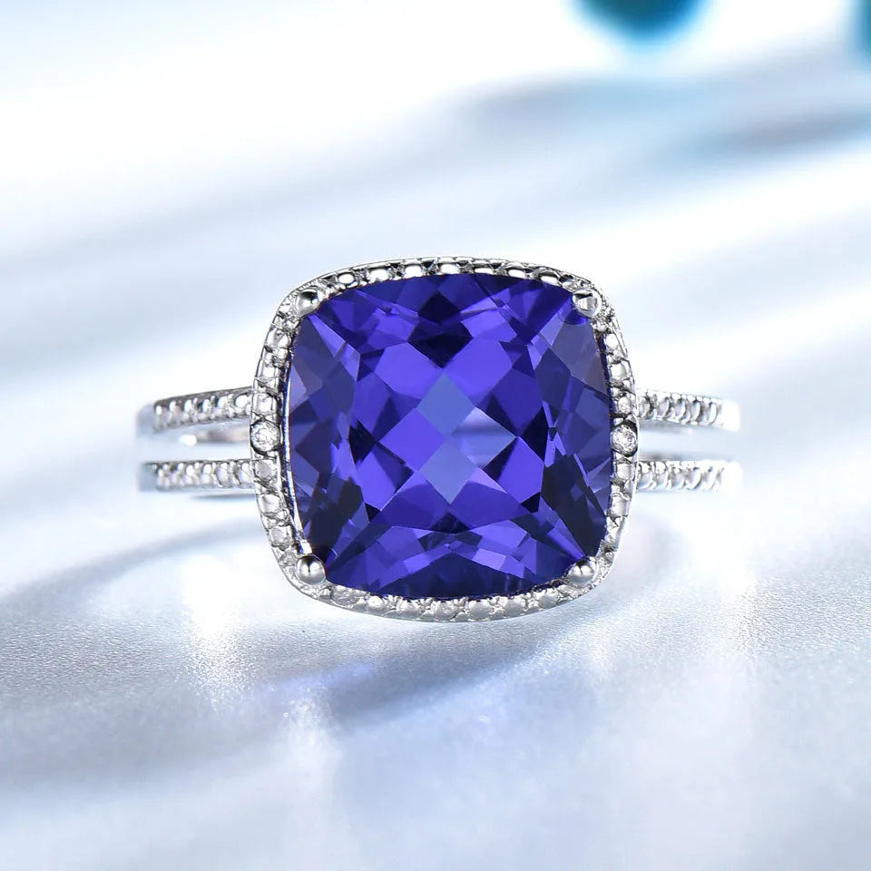 Close-up of a blue tanzanite stone set in a sterling silver women's ring on a grey background.