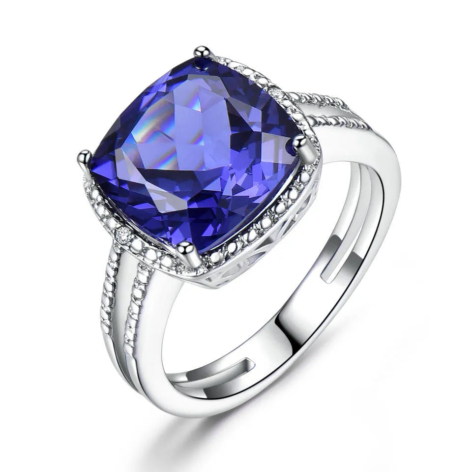 Close-up of a blue tanzanite stone set in a sterling silver women's ring on a grey background.