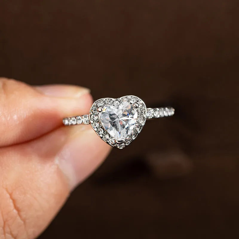 Close-up of a women's heart-shaped ring with a clear crystal centre in rose gold or silvery finish.