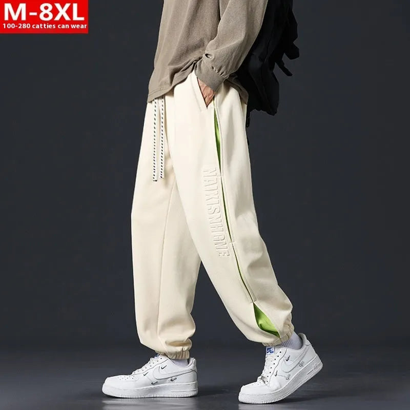 Man wearing loose grey-green trousers with stitching print detail and ankle banding.