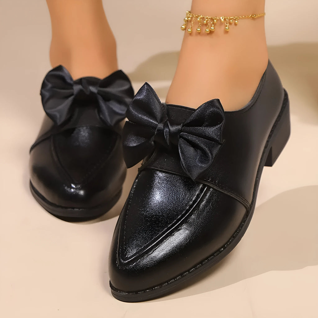 Women's brown leather-look shoes with a decorative bow detail on a flat rubber sole