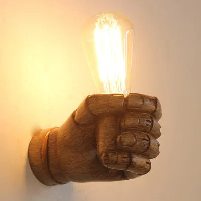 Sculptural resin fist wall lamp in black, white, or wood grain finish for decorative lighting.