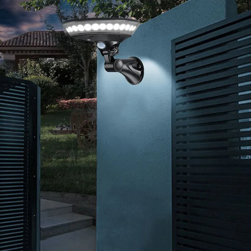 White 360-degree solar-powered outdoor light with motion sensor on a black stake for garden installation.