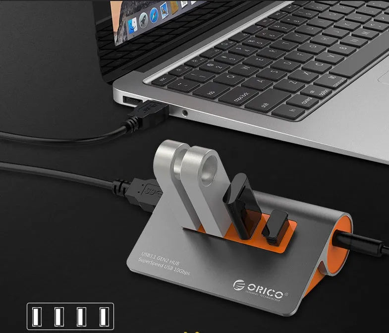 Dark grey and orange aluminium USB hub with four ports and a long black data cable.