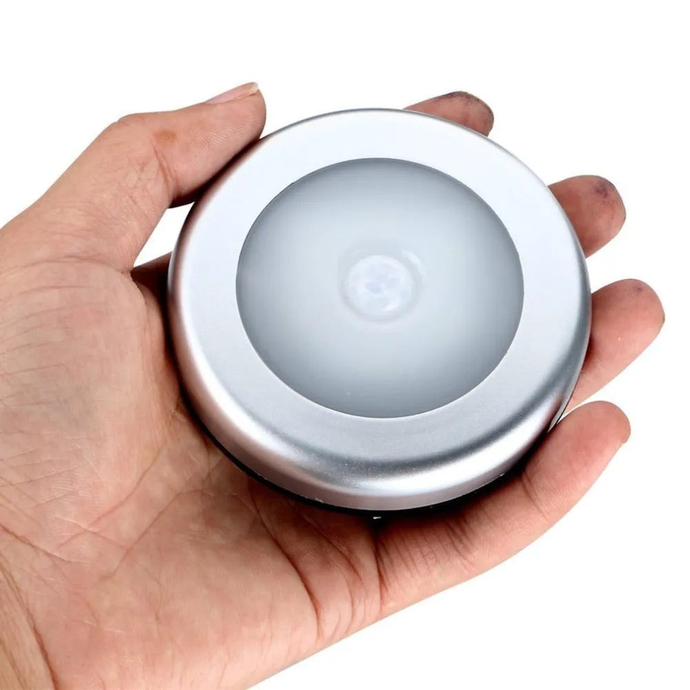 Silver round wireless motion sensor LED night light with adhesive back.