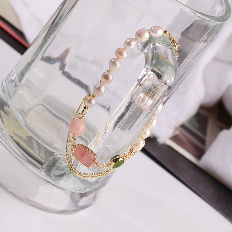 Close-up of a women's pink freshwater pearl bracelet with geometric links and strawberry crystal charms.