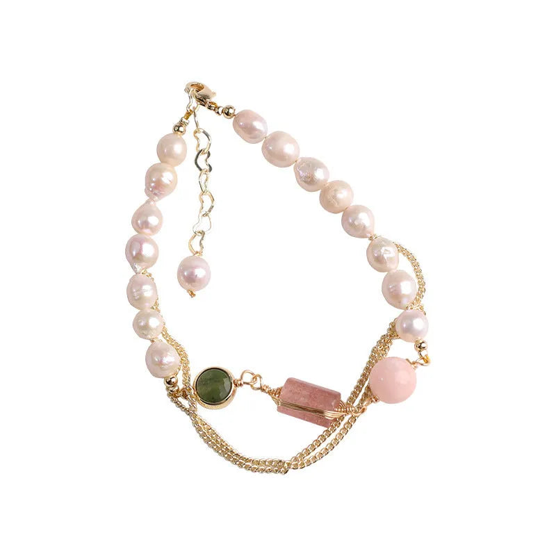 Close-up of a women's pink freshwater pearl bracelet with geometric links and strawberry crystal charms.