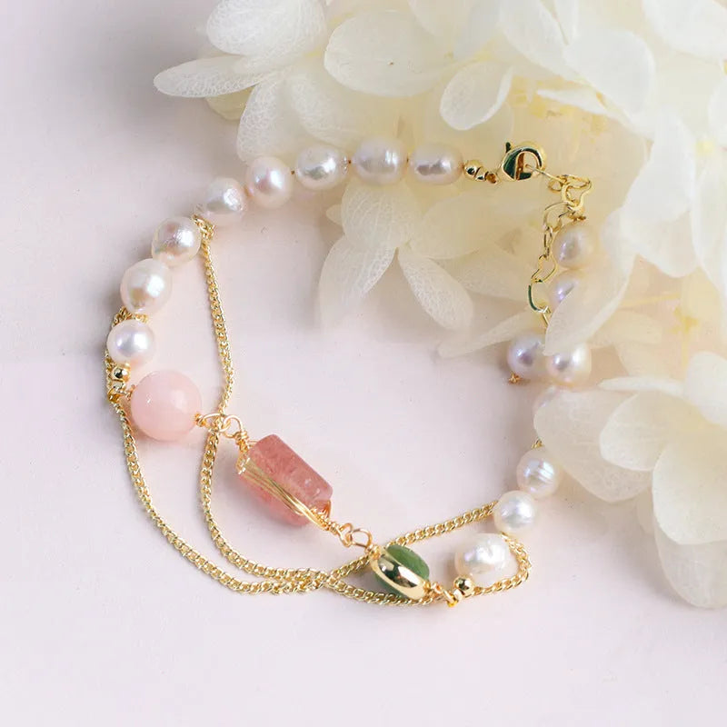 Close-up of a women's pink freshwater pearl bracelet with geometric links and strawberry crystal charms.